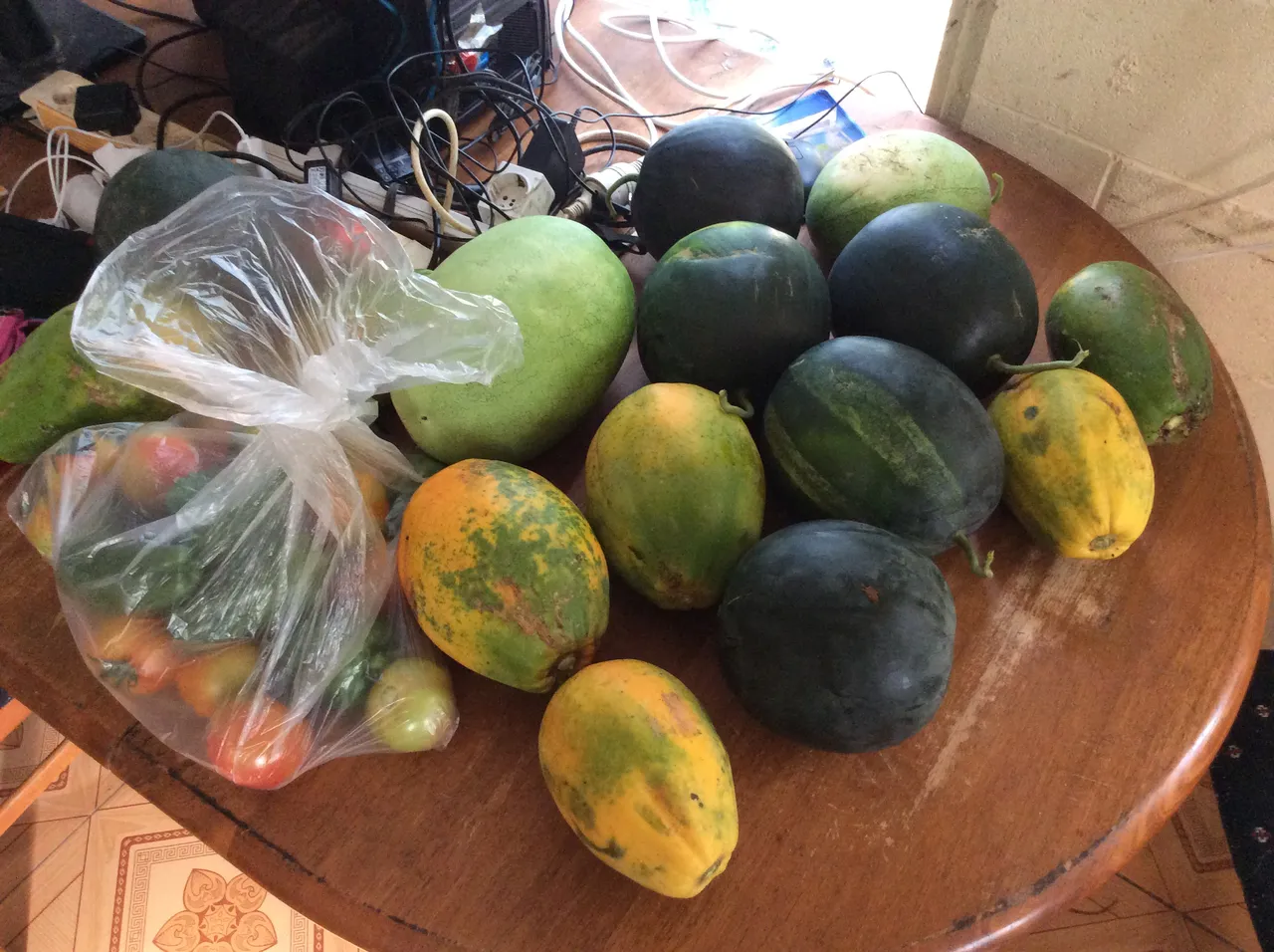 A table covered with watermelons, papayas, tomatoes and peppers