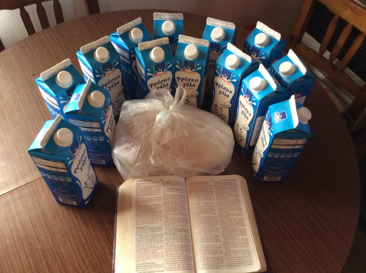 Cartons of milk and a bag of fish on the table, with a Bible open in front of them